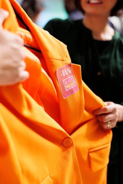 Photo people falling into shopping madness during black friday sales. two angry mad shoppers fighting for orange blazer in department clothing store, going crazy during seasonal sales