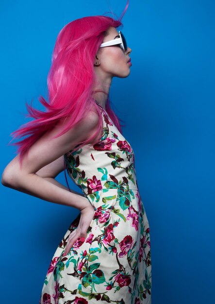 파란색 배경 위에 분홍색 머리와 큰 선글라스를 쓴 사람과 패션 컨셉 패션 모델