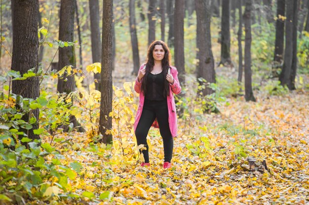 People, fashion and nature concept - plus size woman standing in autumn park