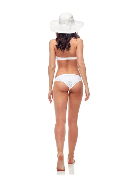 people, fashion, swimwear, summer beach and beauty concept - young woman in white bikini swimsuit from back