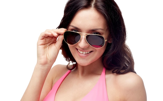люди, мода, купальники, лето и пляжная концепция - счастливая молодая женщина в солнечных очках и розовом купальнике смотрит на тебя