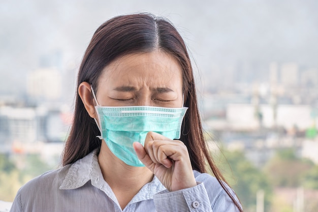 写真 人は大気汚染で気分が悪くなり、環境は有害または有毒な影響を及ぼします。空気中の汚染レベルが高まっているため、自分を守るためにマスクを着用している街の女性。