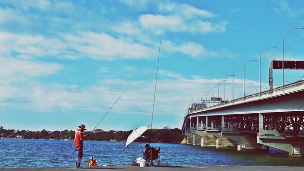 People fishing in sea against the sky