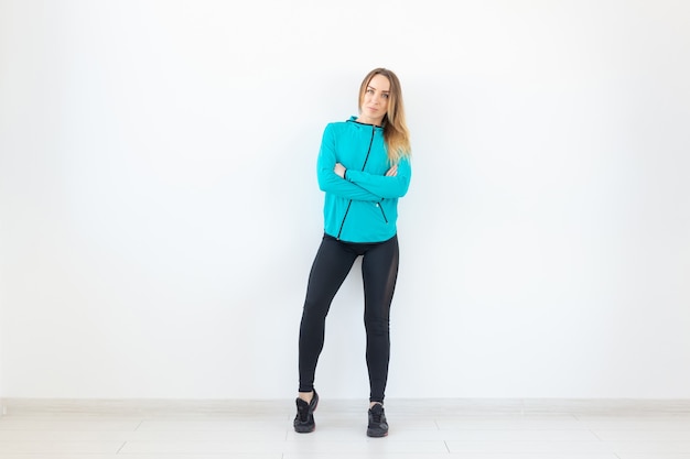 People, fitness and sport concept - Beautiful fit woman dressed in sportswear posing over white background