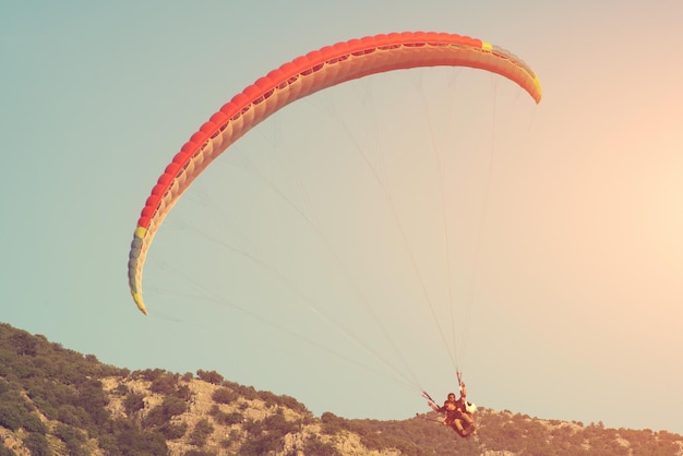 People flying a paraglider in the sky over the mountains