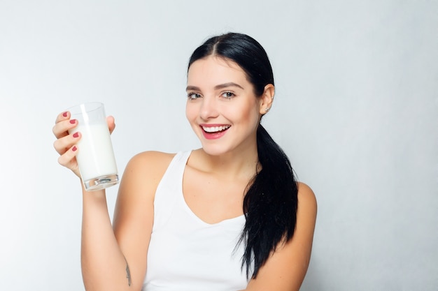 Persone, cibo, bellezza, stile di vita, moda e concetto sensibile - latte - donna che beve latte, bella giovane donna felice e sorridente che si gode un bicchiere di latte