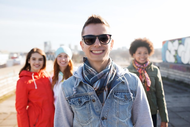 people, friendship and international concept - happy young man or teenage boy in front of his friends on city street