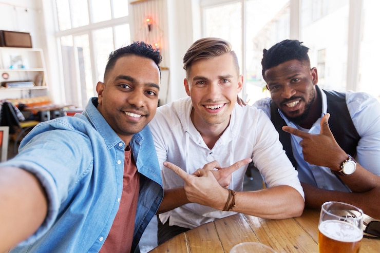 Photo people, friendship and leisure concept - happy male friends drinking beer and taking selfie at bar or pub