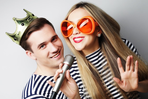 people friendship love and leisure concept beautiful young loving couple with microphone Big orange glasses and crown Ready for party