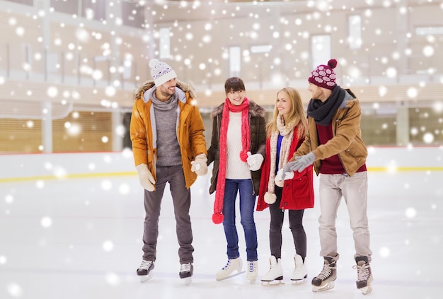 people, friendship, sport and leisure concept - happy friends on skating rink