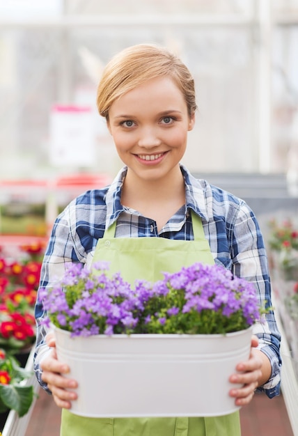 人、ガーデニング、職業のコンセプト – 温室で花を持つ幸せな女性や庭師