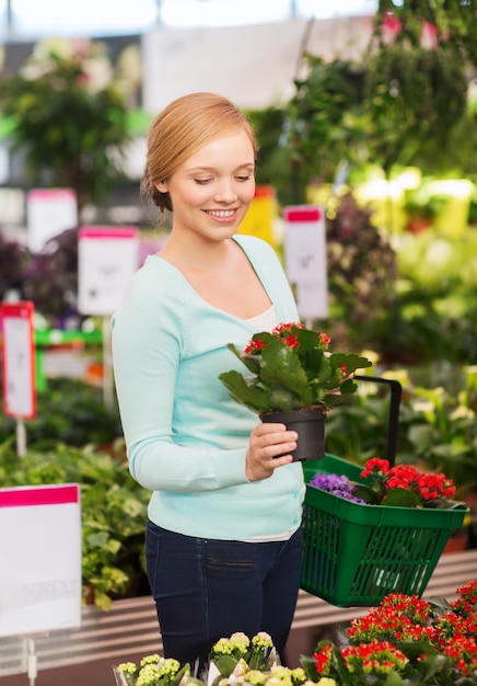 Concetto di persone, giardinaggio, shopping, vendita e consumismo - donna felice con cesto che sceglie e compra fiori in serra