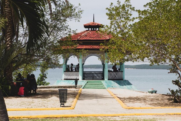 Photo people in gazebo against sea during sunny day