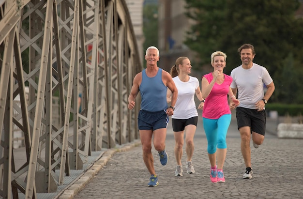 La gente raggruppa la squadra di corridori da jogging durante l'allenamento mattutino con l'alba sullo sfondo