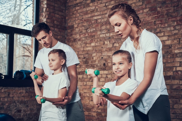 People in the gym with dumbbells in white T-shirts