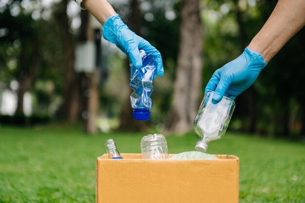 ゴミボトルのプラスチックとガラスをリサイクルバッグに入れる人々の手 公害の生態学とプラスチックの概念xA