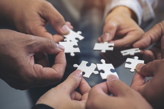 people hands holding a jigsaw puzzle in circle together