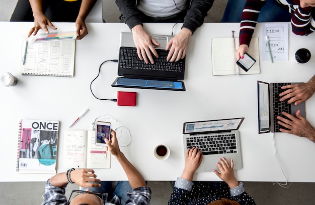 Mani della gente che lavorano facendo uso del computer portatile sulla tabella bianca