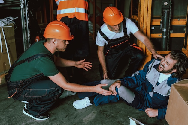 People in Hardhats Worried about Coworker Lying on Floor