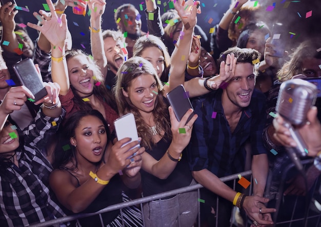 Foto persone che si divertono e fanno foto a un concerto con coriandoli 3d