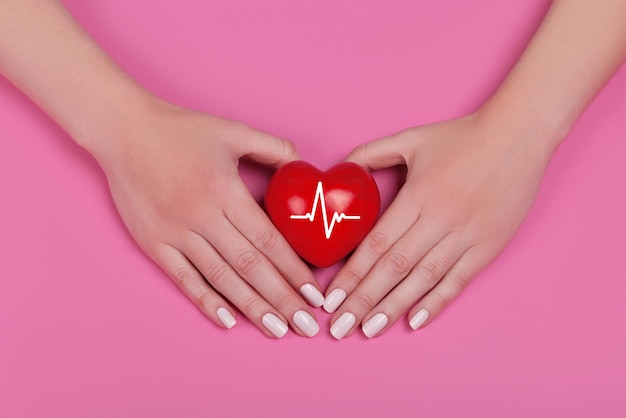 People health concept - close up of woman's cupped hands showing red heart with heart beat.