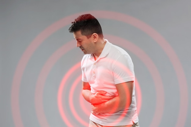 Photo people, healthcare and health problem concept - unhappy man suffering from stomach ache over gray background