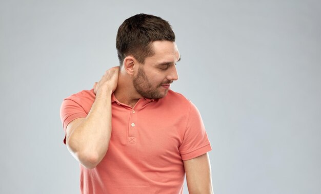 Photo people, healthcare and problem concept - unhappy man suffering from neck pain over gray background