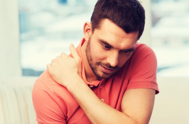 Foto persone, assistenza sanitaria e concetto di problema - uomo infelice che soffre di dolore al collo a casa