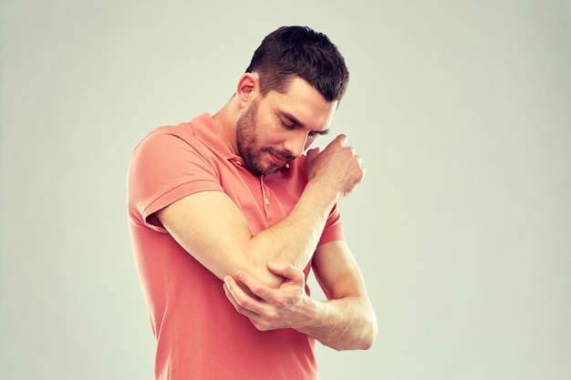 people, healthcare and problem concept - unhappy man suffering from pain in hand over gray background