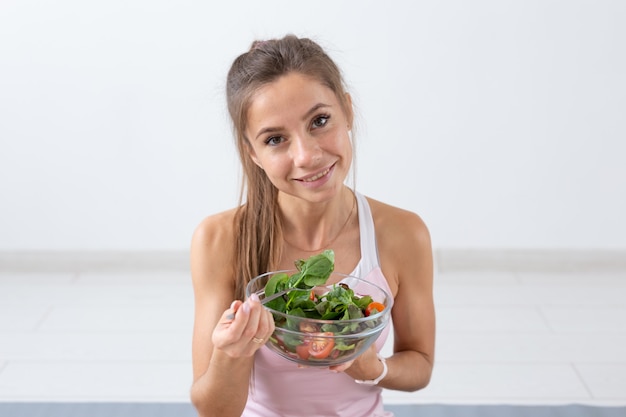 People, healthy lifestyle and fitness concept - Beautiful young woman after workout eating healthy