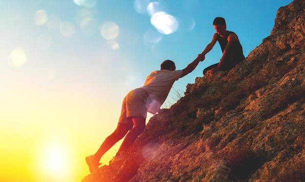 people helping each other hike on the mountain