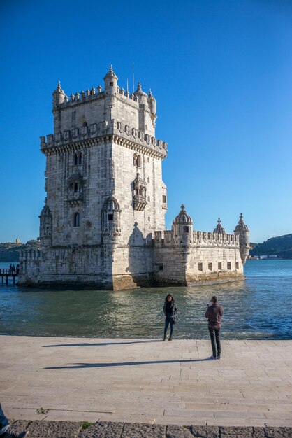 People at historical building against clear sky