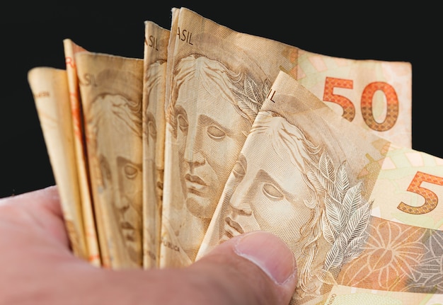 Photo a people holding a brazilian banknotes of brazilian real