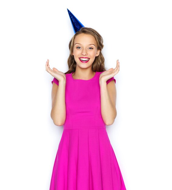 people, holidays and celebration concept - happy young woman or teen girl in pink dress and party cap