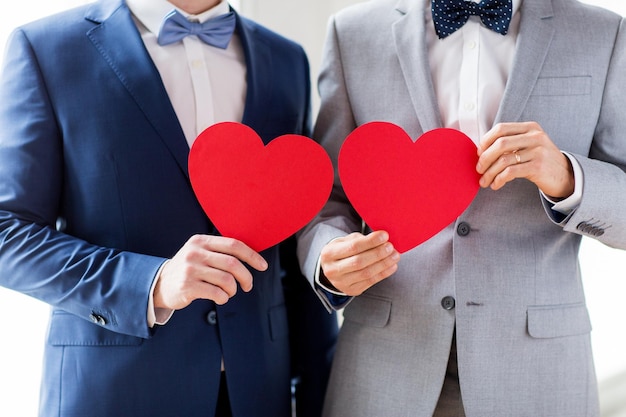 사람들, 동성애, 동성 결혼, 발렌타인 데이 및 사랑 개념 - 결혼식에서 붉은 종이 하트 모양을 들고 있는 행복한 결혼한 남성 게이 커플의 클로즈업