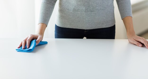 Concetto di persone, lavori domestici e pulizie - primo piano del tavolo per la pulizia delle mani della donna con un panno a casa