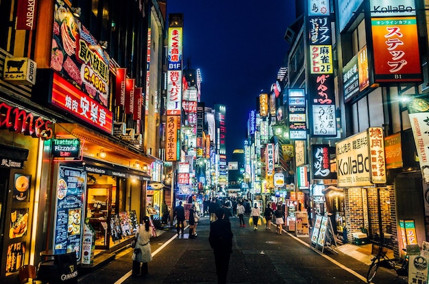 Gente sulla strada illuminata della città di notte