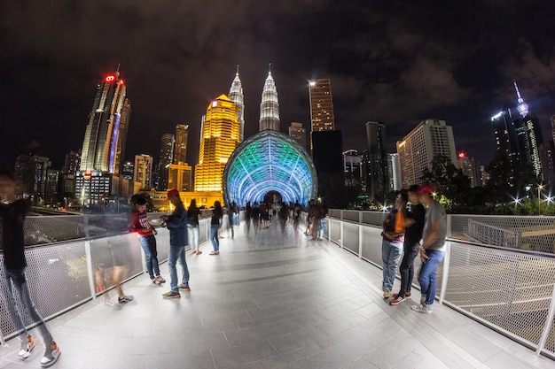 Photo people on illuminated modern buildings in city at night