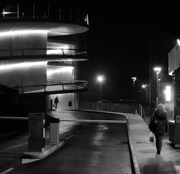 People on illuminated sidewalk in city at night