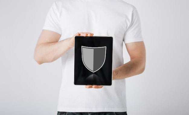 Photo people, internet security and cyber protection concept - close up of man with virtual antivirus program shield icon on tablet pc computer screen over gray background