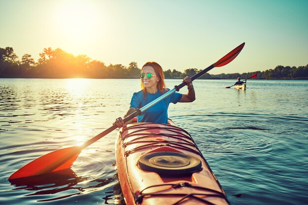 People kayak during sunset in the background. Have fun in your free time.