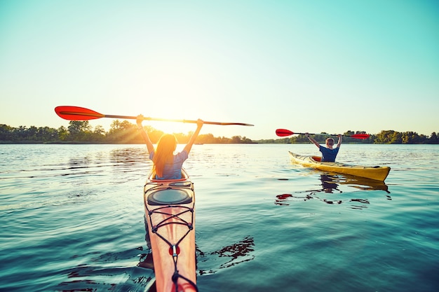 People kayak during sunset in the background. Have fun in your free time.