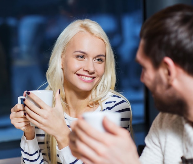 人々、レジャー、コミュニケーション、飲食のコンセプト-幸せなカップルの出会いとカフェでお茶やコーヒーを飲む