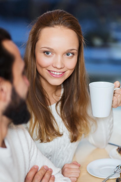 人々、レジャー、コミュニケーション、飲食のコンセプト-幸せなカップルの出会いとカフェでお茶やコーヒーを飲む