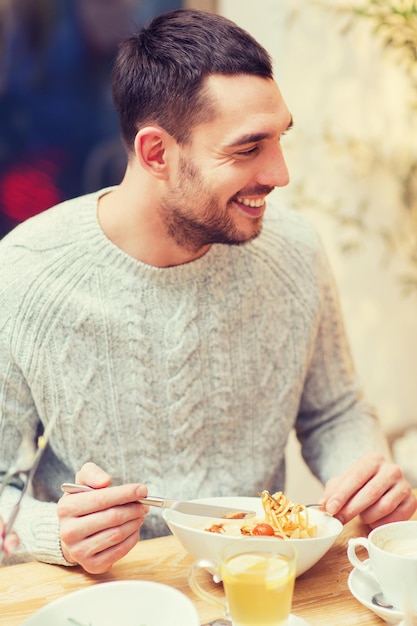 人々、レジャー、食事、食べ物の概念-レストラン、カフェ、または家で夕食をとる幸せな若い男