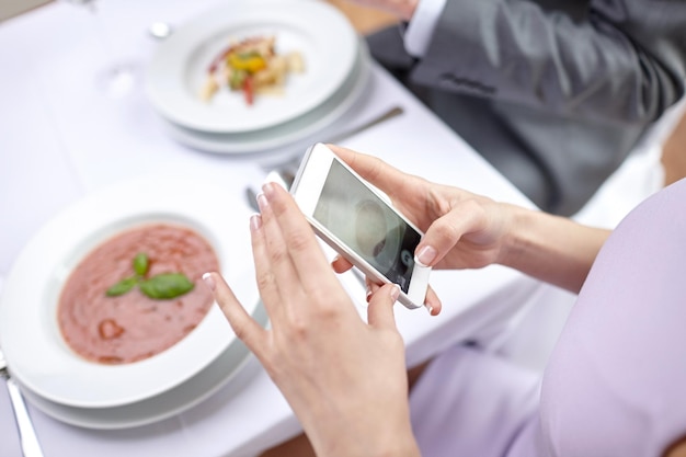 사람, 여가, 식사, 기술 개념 - 레스토랑에서 음식 사진을 찍는 스마트폰을 가진 커플