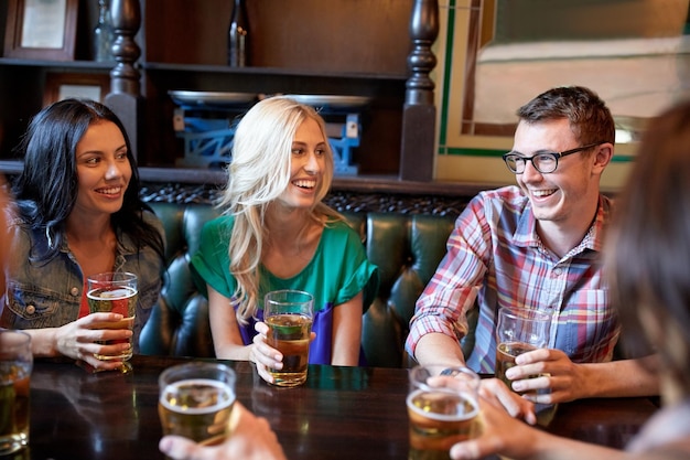 사람, 레저, 우정, 커뮤니케이션 개념 - 행복한 친구들이 맥주를 마시고 술집이나 술집에서 이야기를 나눕니다.