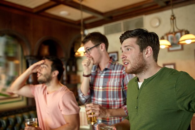 사람, 레저, 우정, 스포츠 개념 - 스포츠 경기나 축구 경기를 보고 술집이나 술집에서 맥주를 마시는 남자 친구를 화나게 합니다.