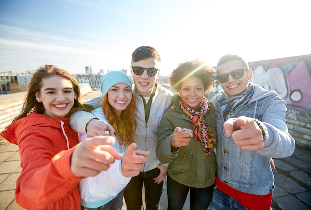 Photo people, leisure, gesture and teenage concept - group of happy teenage friends pointing fingers at you on city street