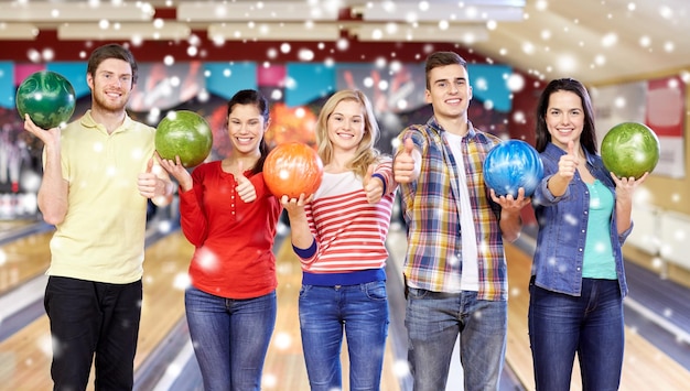 Concetto di persone, tempo libero, sport, amicizia e intrattenimento - amici felici nel club di bowling durante la stagione invernale